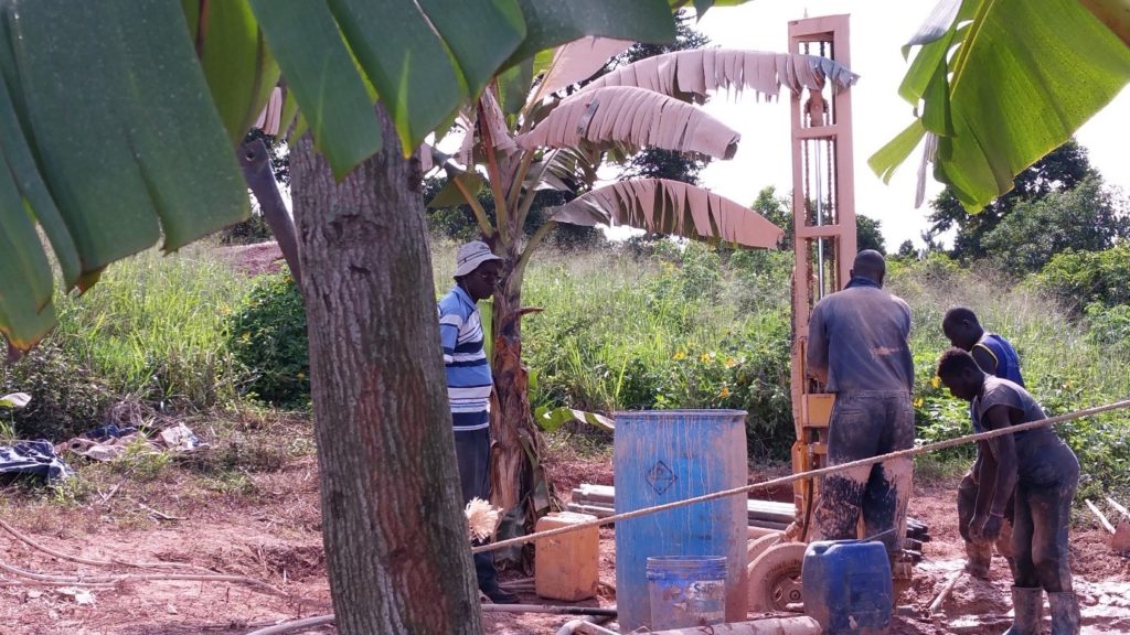 John Okwi (left, with hat), the owner of PAT-DRILL Uganda, is supervising his team of drillers using a PAT-301 to drill through the weathered basement near the top of Makerere hill